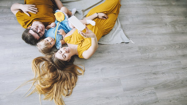 kedves fiatal család mosolyog a laminált padlón fekve