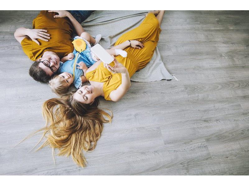 kedves fiatal család mosolyog a laminált padlón fekve